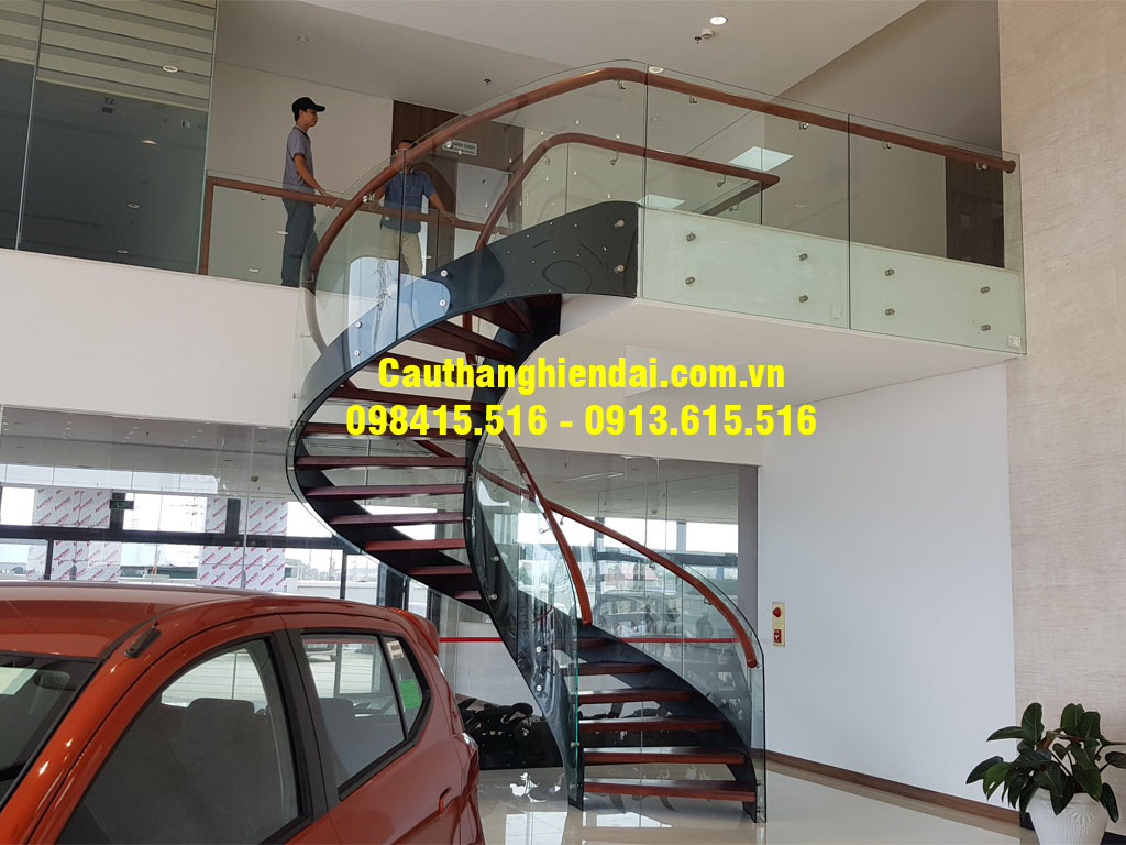 Mẫu cầu thang xương cá xoắn hiện đại và đẹp nhất, kính cong nghệ thuật, tay vịn gỗ lim nam phi
