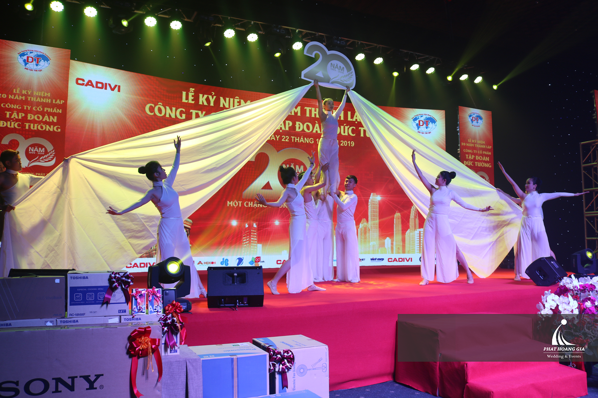Vũ đoàn biểu diễn tiết mục nghệ thuật trên sân khấu lễ kỷ niệm doanh nghiệp với đạo cụ vải sân khấu và đội hình được dàn dựng công phu